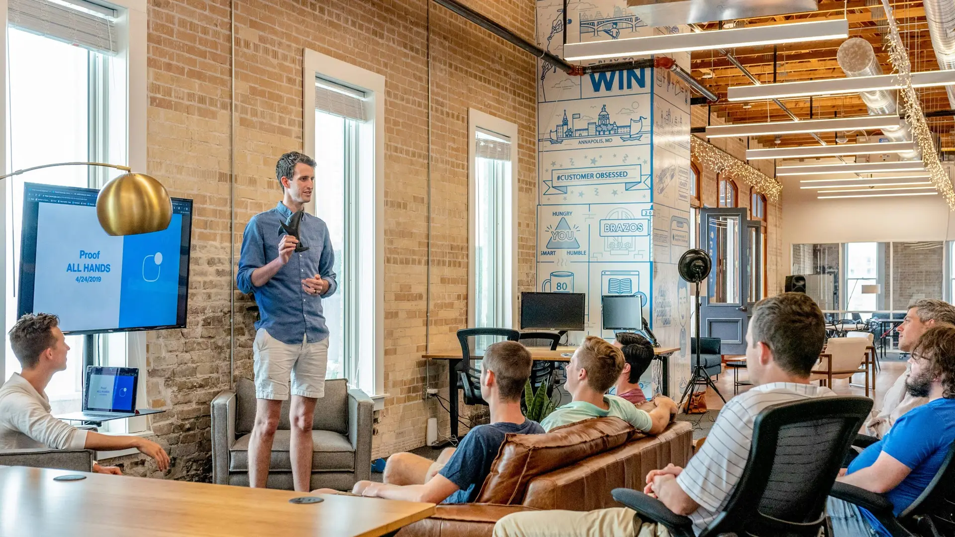 Presenter discusses custom hockey trading pin designs and Cooperstown pins in a modern office meeting at ThePinCreator.com.